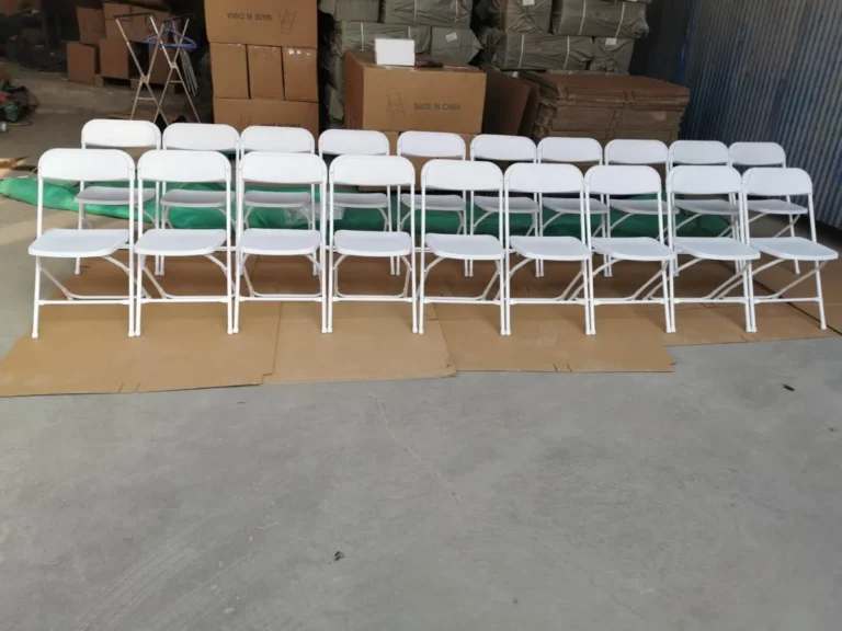 White folding chairs lined up in a warehouse before delivery